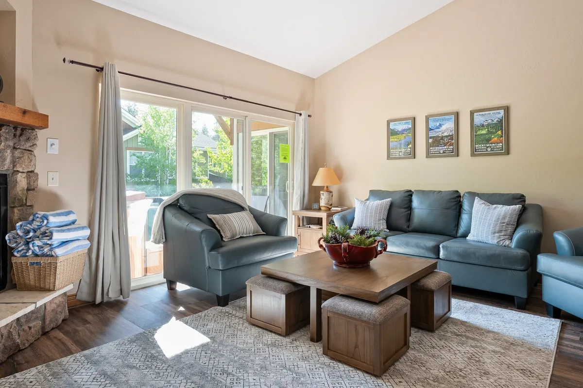 A stylish, comfortable seating area with an inviting sofa, decorative coffee table, and art-adorned walls. Sunlight streams through expansive windows, filling the room with natural warmth. The space is ideal for informal conversations, reading, or enjoying board games with loved ones.