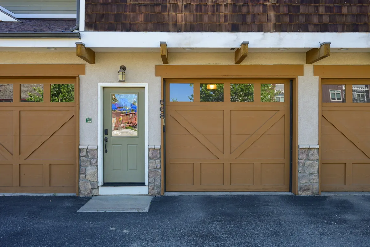 A friendly exterior shot of the property featuring the front door, stonework, and garage doors, set in a welcoming neighborhood. The view hints at inviting walks and easy access to surrounding amenities.