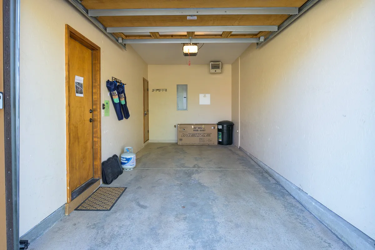A functional garage interior featuring organized storage for equipment, a wooden door, storage bins, and tool hangers. The space is tidy and ready for storing outdoor gear or parking a vehicle.
